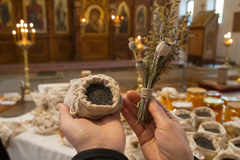Открытый полотняный мешочек с чёрным маком и маковейчик из трав в руке прихожанина у престола — освящение мака на Медовый Спас в храме