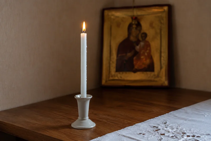 Руки матери держат свечу у иконы, тёплый свет, никаких лиц крупным планом — почему материнская молитва о детях считается особой