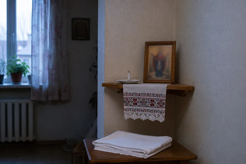 Икона Покрова Богородицы общим планом на полке в углу, рядом догоревшая короткая свеча и сложенный платок, спокойный вечерний свет из окна — что важно понимать