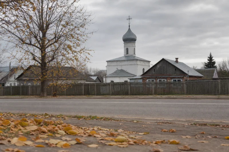 Небольшой православный храм издалека на пустой осенней улице, опавшие листья на земле — Усекновение главы Иоанна Предтечи 11 сентября