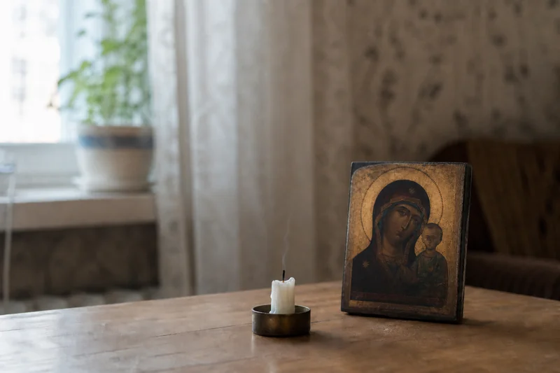 Догоревшая восковая свеча и небольшая икона на столе в утреннем свете — благодарственная молитва после успешной операции