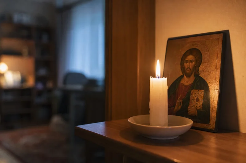 Зажжённая свеча перед небольшой иконой на полке — как усилить защиту от клеветы и злого языка