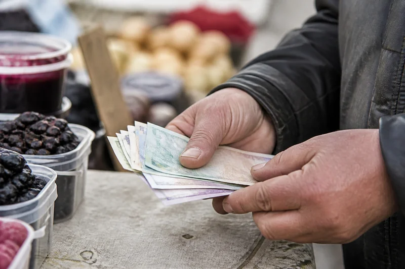 Продавец за прилавком считает сдачу, руки крупным планом, лица не видно — как читают заговор на рынке и при продаже через интернет